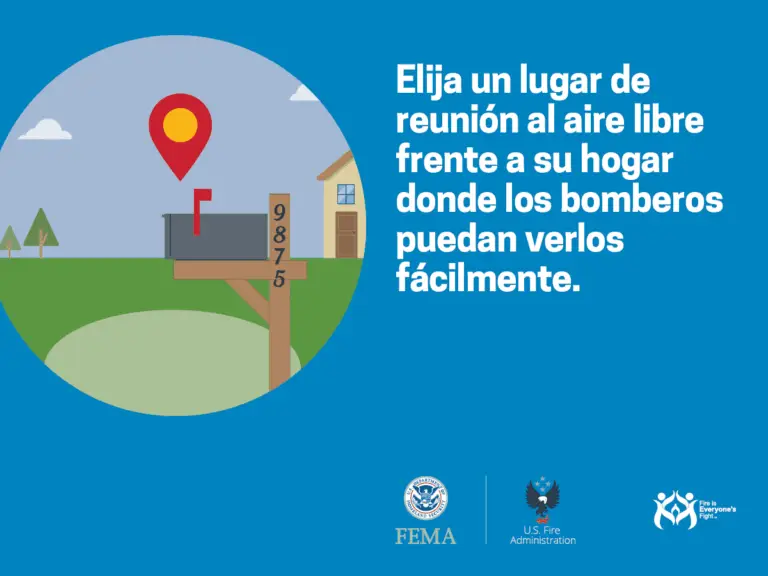 A Spanish-language poster advises choosing an outdoor meeting place in front of your home where firefighters can see you easily. It shows a house, trees, a mailbox with numbers "9875", and a location pin. Logos of FEMA, U.S. Fire Administration, and the Fire is Everyone’s Fight campaign are at the bottom.