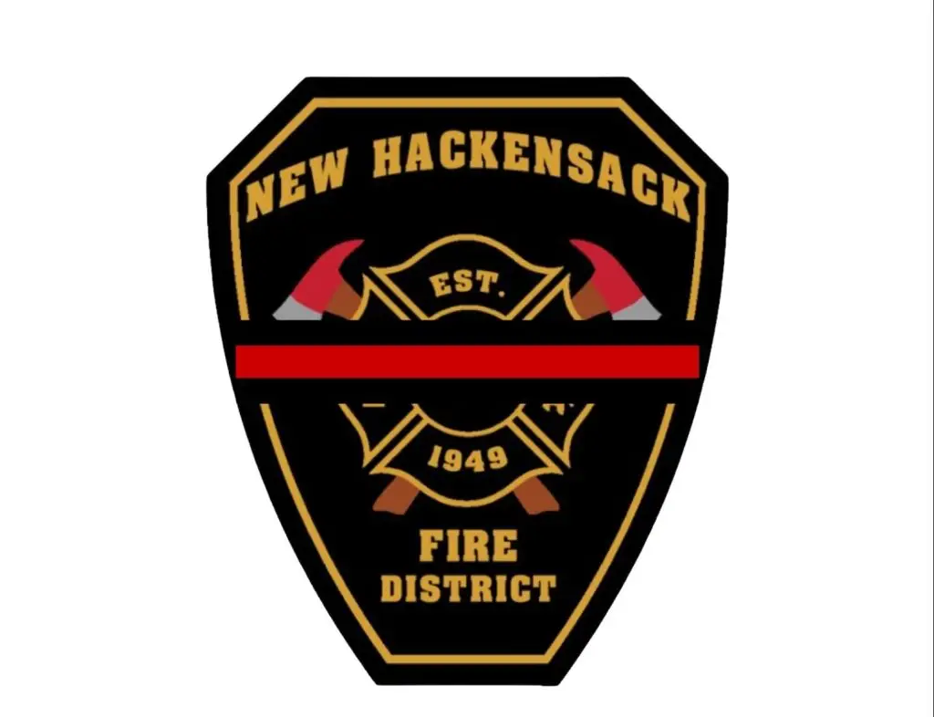 A black and gold badge with "New Hackensack Fire District" written in gold text. It features two crossed fire axes, the establishment year of 1949, and a central red line.